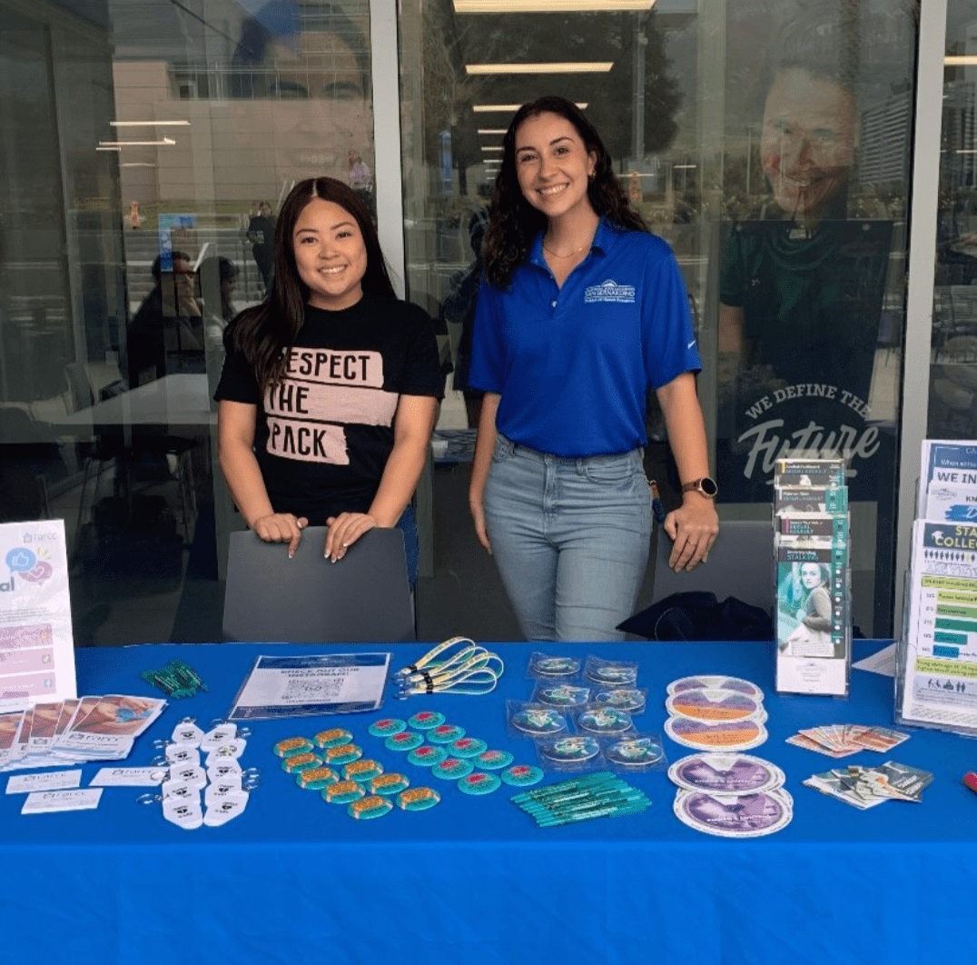 Two OCRT staff stand behind table with resources